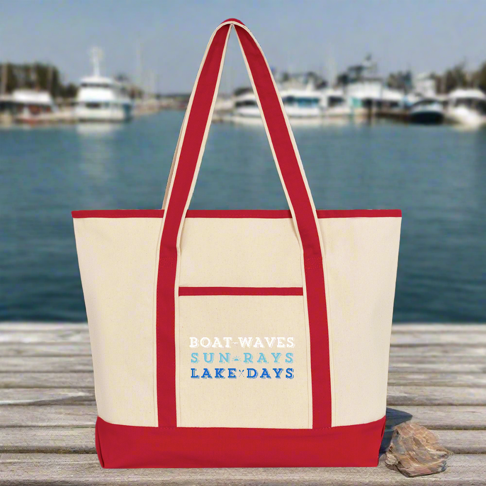 Beige tote bag with red handles and text on a wooden dock with water and boats in the background